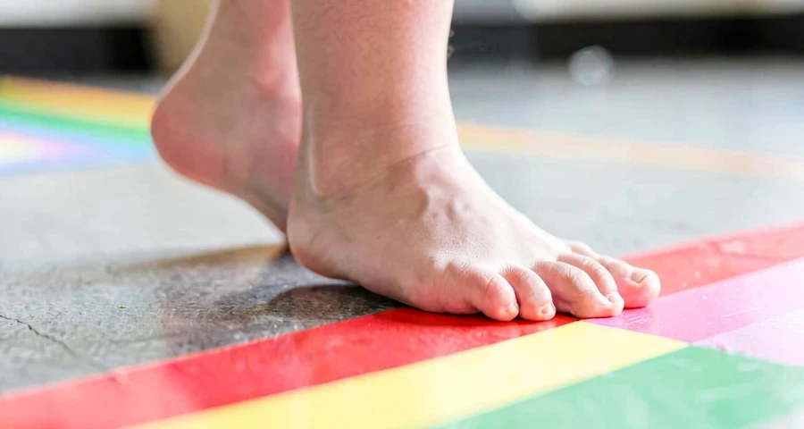 pés de criança caminhando com equilíbrio sobre linha marcada na creche