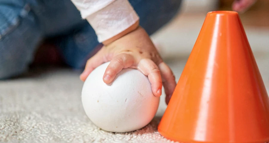 criança da creche tocando bola com o pé durante atividade motora na creche