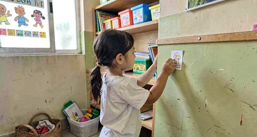 criança da creche fixando etiqueta em cantinho da sala