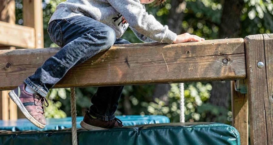 aluno escalando estrutura baixa de aventura com colchonetes de segurança