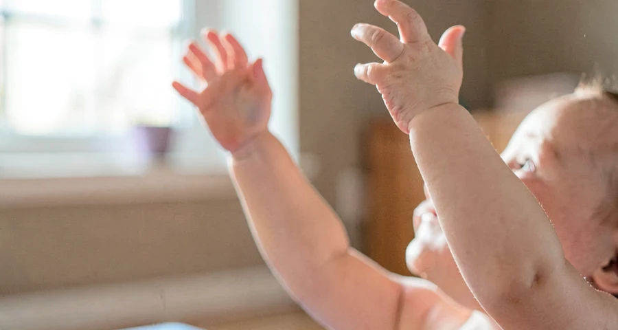 bebê esticando os braços para cima durante atividade motora na creche