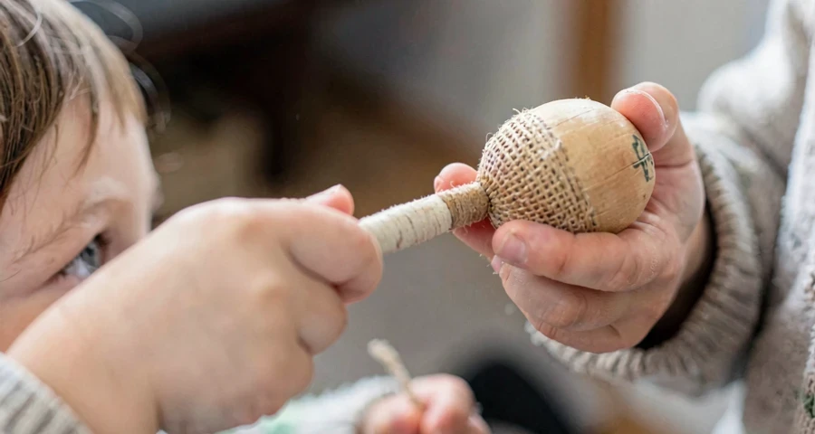 criança experimentando chocalho artesanal em atividade musical na pré-escola