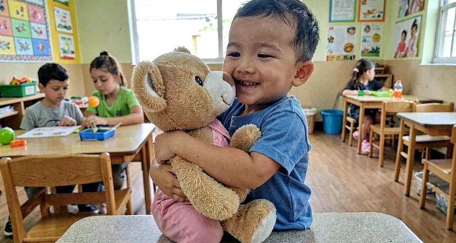 bebê abraçando bichinho de pelúcia durante atividade de segurança emocional na creche