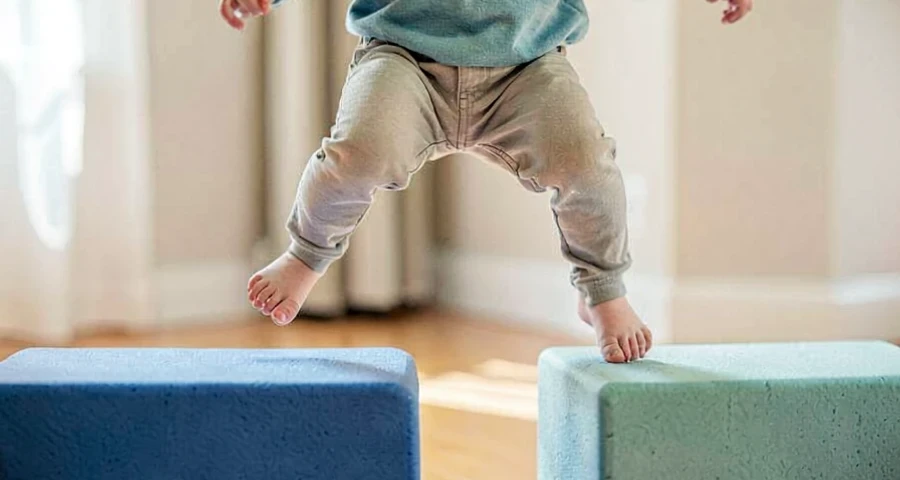 criança da creche pulando entre blocos de espuma durante atividade motora na creche