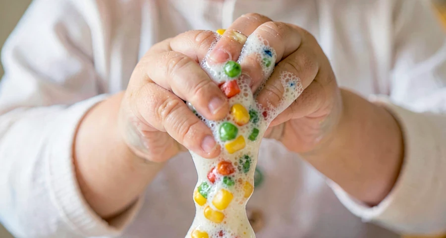 mão de bebê apertando massa sensorial colorida em atividade na creche